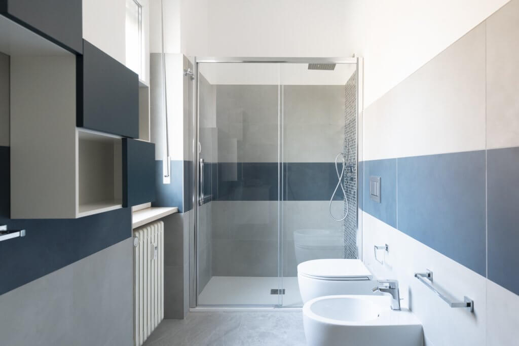 Bagno con rivestimenti in gres, box doccia con vetro e sanitari dal design moderno