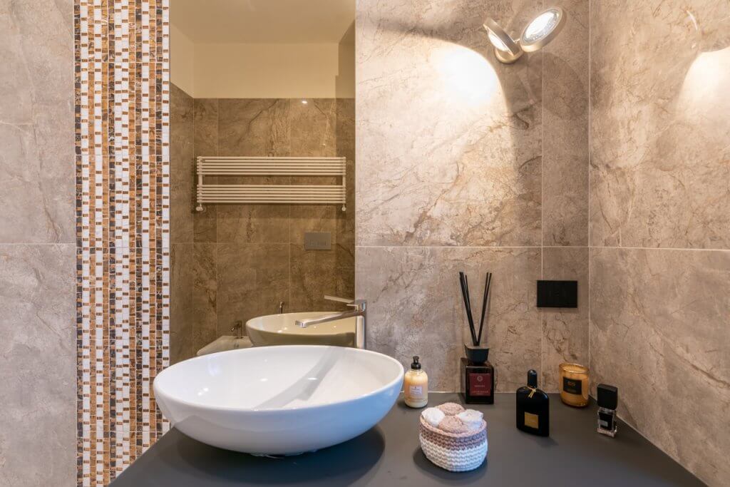 Bagno con lavabo bianco rivestimenti in marmo, e tasselli colorati