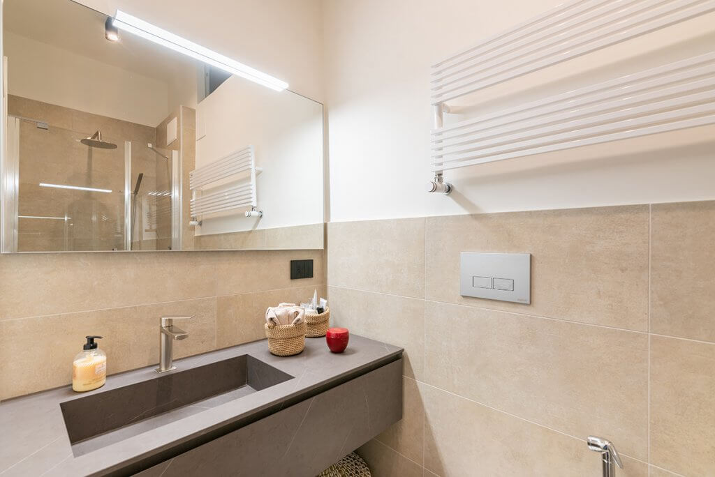 Bagno con rivestimenti in gres con specchio retroilluminato