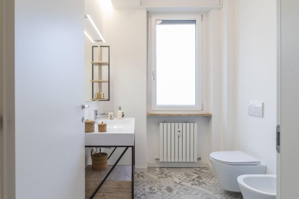 Bagno con rivestimenti in gres per il pavimento, sanitari bianchi a sospensione, lavandino dal design moderno