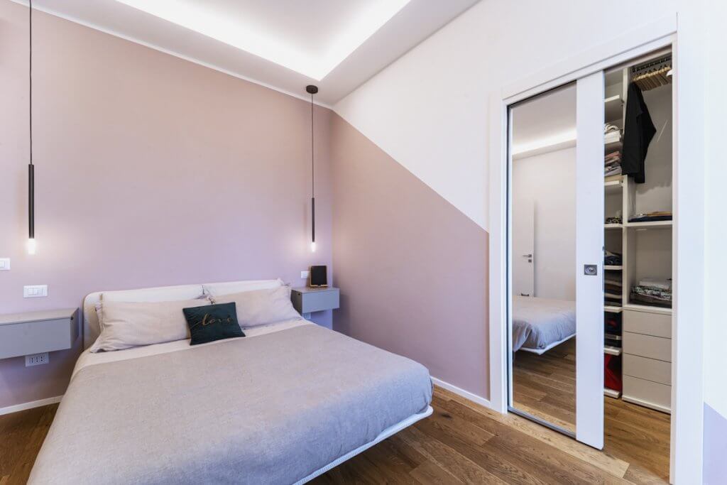 Camera da letto moderna con cabina armadio, pareti rosa, parquet in rovere spazzolato