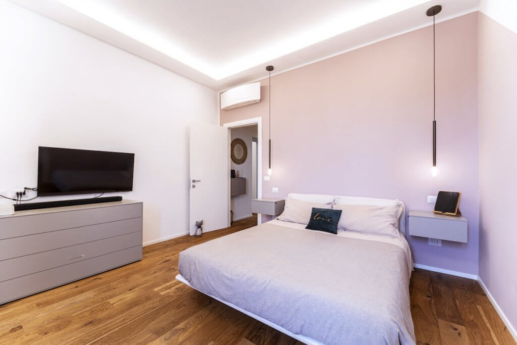 Camera da letto moderna con cabina armadio, pareti rosa, parquet in rovere spazzolato