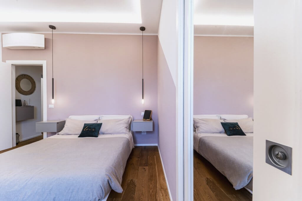 Camera da letto moderna con cabina armadio, pareti rosa, parquet in rovere spazzolato