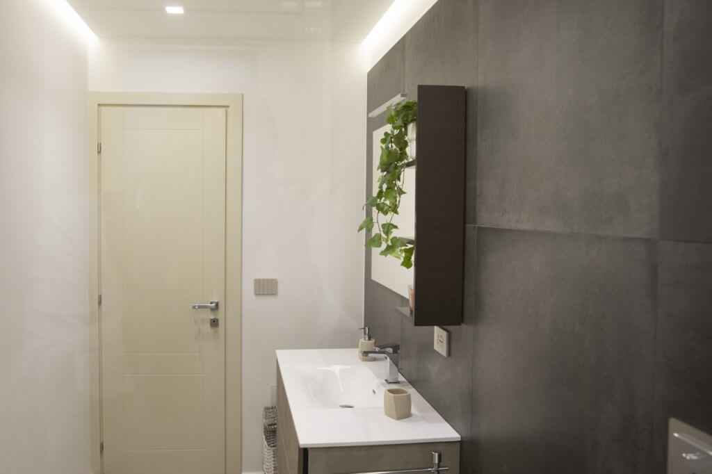 Bagno con lavabo bianco e piastrelle scure in formato maxi